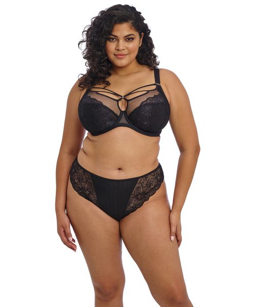 BRIANNA_BLACK_UW-PLUNGE-BRA_EL8080_THONG_EL8087_F_TRADE_3000_SS25 Kobieta o pełnych kształtach w czarnym komplecie: biustonosz z fiszbinami z ozdobnymi paseczkami i figi z koronką