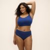 DOWNTIME_FRENCH-NAVY_NON-WIRED-BRALETTE_EL301417_NERINA_HIGH-LEG-BRIEF_EL302753_F1_TRADE_3000_AW26 Kobieta o pełnych kształtach w granatowym komplecie: miękki biustonosz bez fiszbin i figi z koronkowym wykończeniem