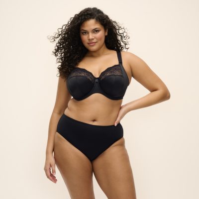 MORGAN_BLACK_UW-BRA_EL4111_SMOOTH_FULL-BRIEF_EL4565_F1_TRADE_3000 Kobieta o pełnych kształtach w czarnym komplecie: gładki biustonosz z fiszbinami z koronką u góry miseczek i wysokie figi