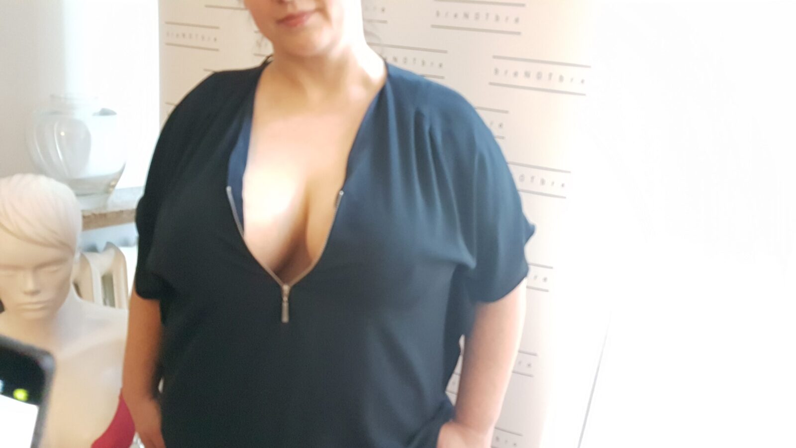 Klientka w salonie w grafitowej sukience z głębokim dekoltem po podklejeniu biustu taśmą